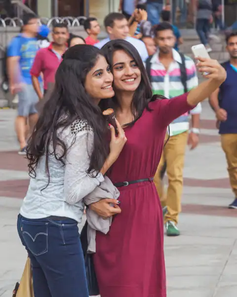 Two young women taking a selfie on a street in Kuala Lumpur