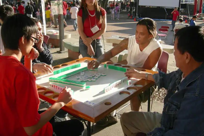 Four people playing mahjong together at an outdoor table at a night market