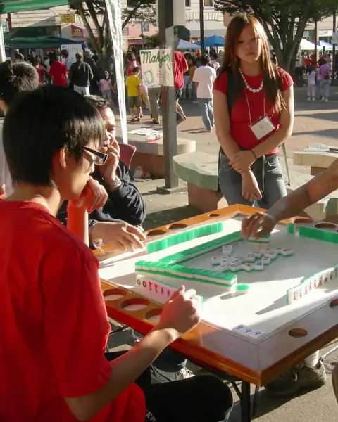 Four people playing mahjong at an outdoor night market