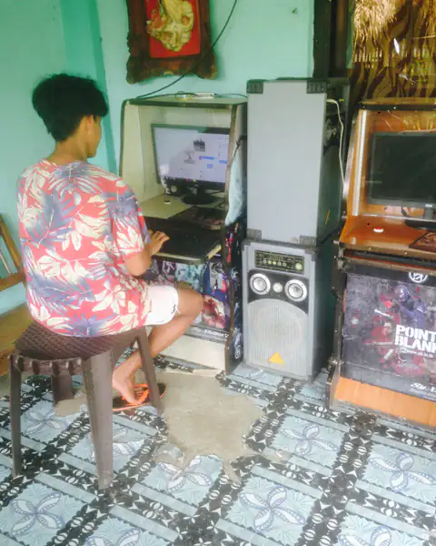 Young Filipino playing at a coin-operated piso net computer