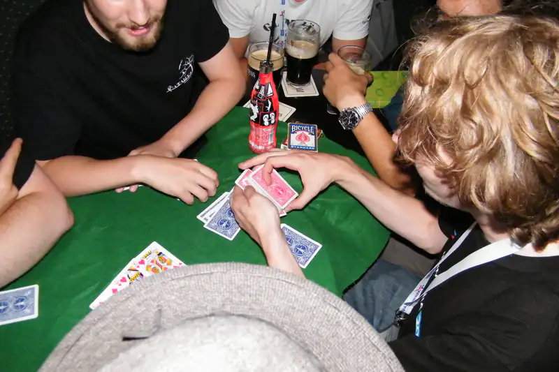 Group of friends playing cards around a green felt table