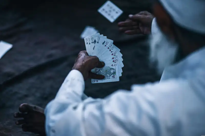 Man holding a fanned hand of playing cards at a dark table