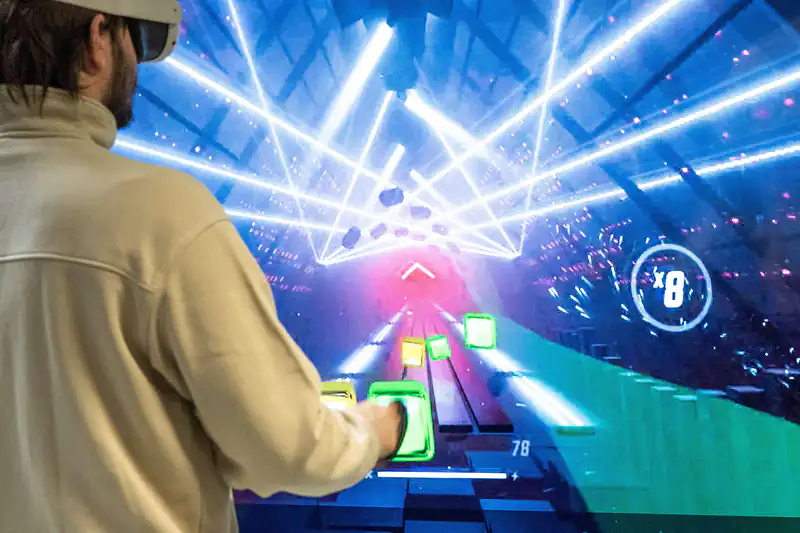 Person wearing a VR headset playing a colourful neon rhythm game