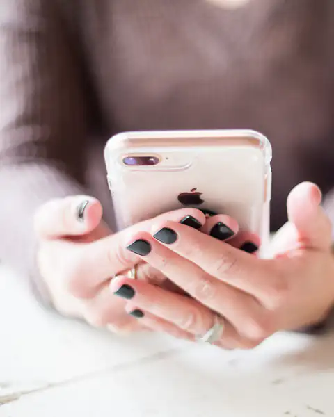 Woman holding an iPhone next to a coffee cup